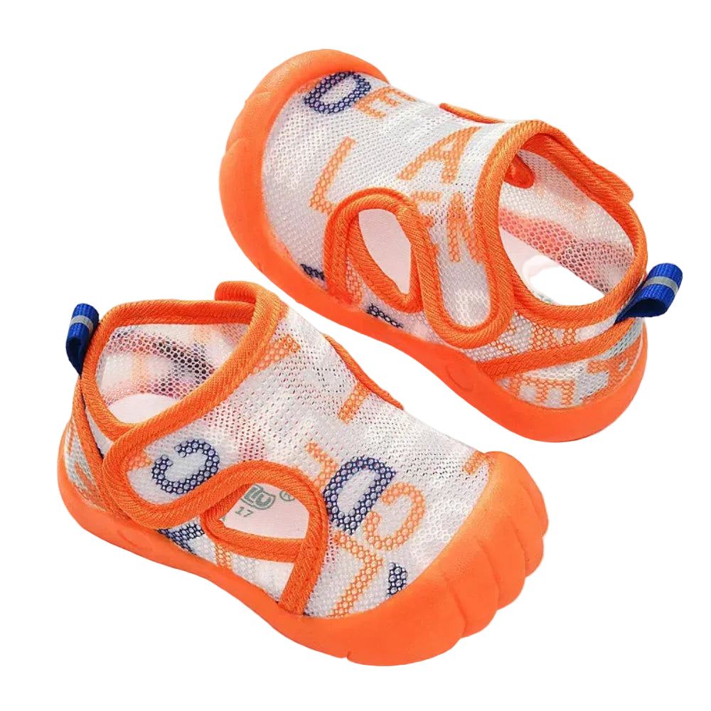 Pair of orange and white baby shoes on a light background