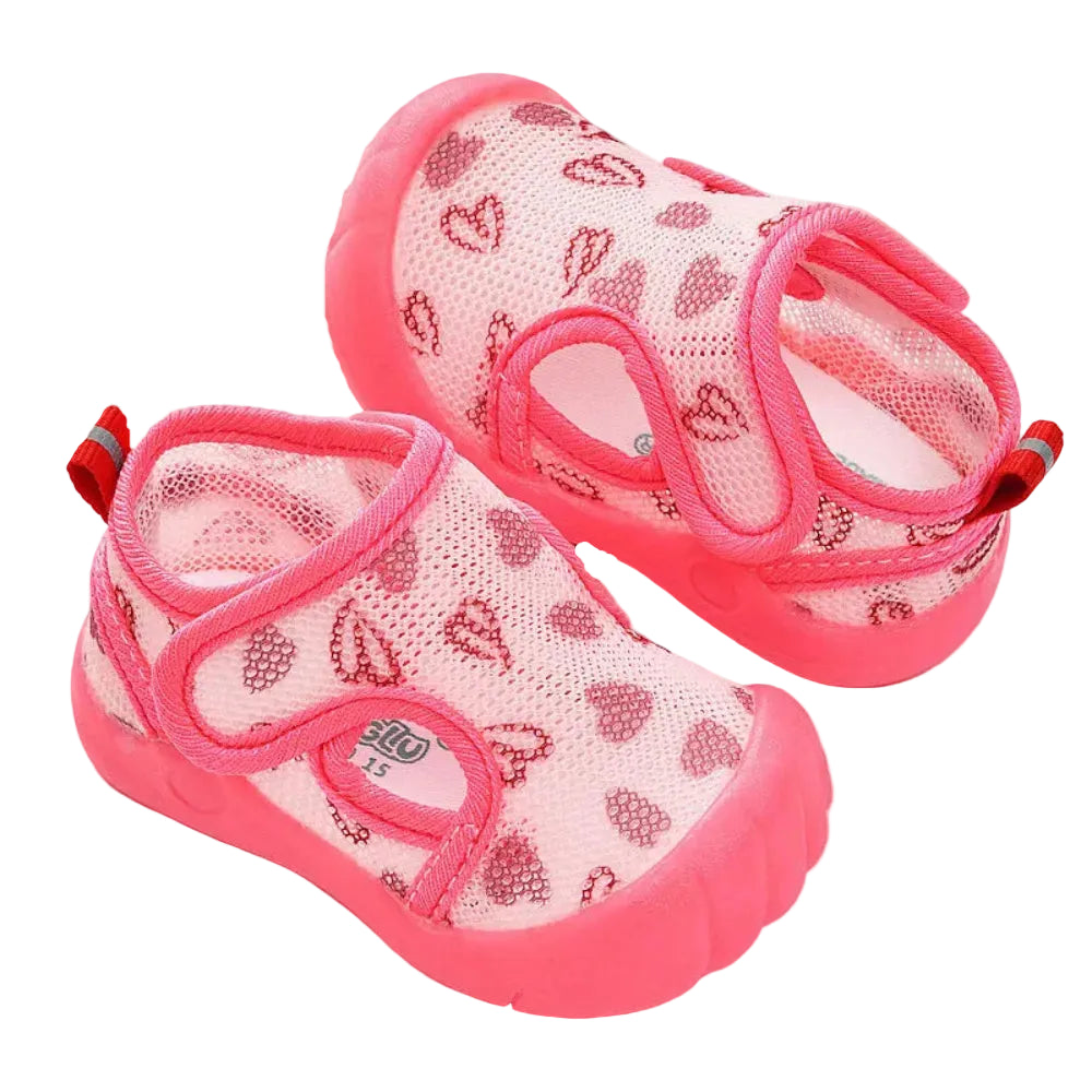 Pair of pink children's sandals with heart patterns on a white background