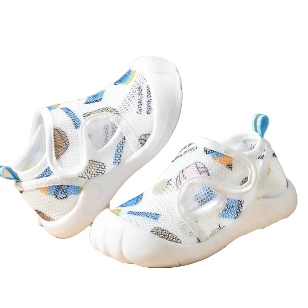 White children's shoes with colorful patterns on a beige surface