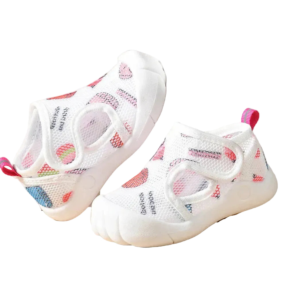 White children's shoes with colorful patterns on a beige background